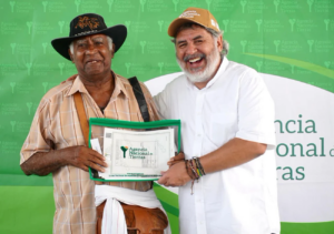 Carlos Lopera stands with another man, both of them holding a certificate.