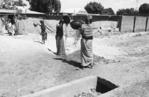 Fulani women working with hand tools on farmland in Nigeria.