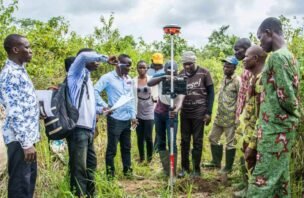 People gather around surveying equipment in Benin