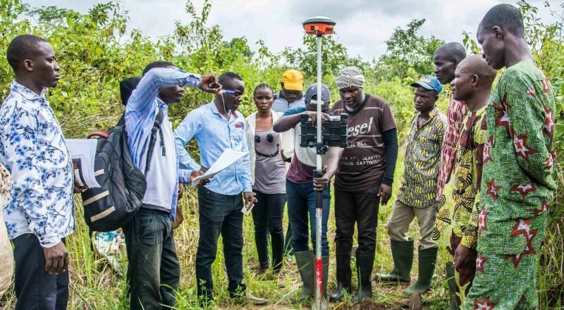 People gather around surveying equipment in Benin