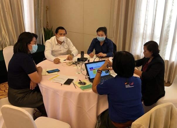 Participants discuss responsible investment around a table at a 2022 dialogue in Laos.