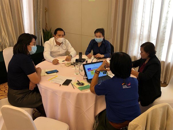 Participants discuss responsible investment around a table in Laos